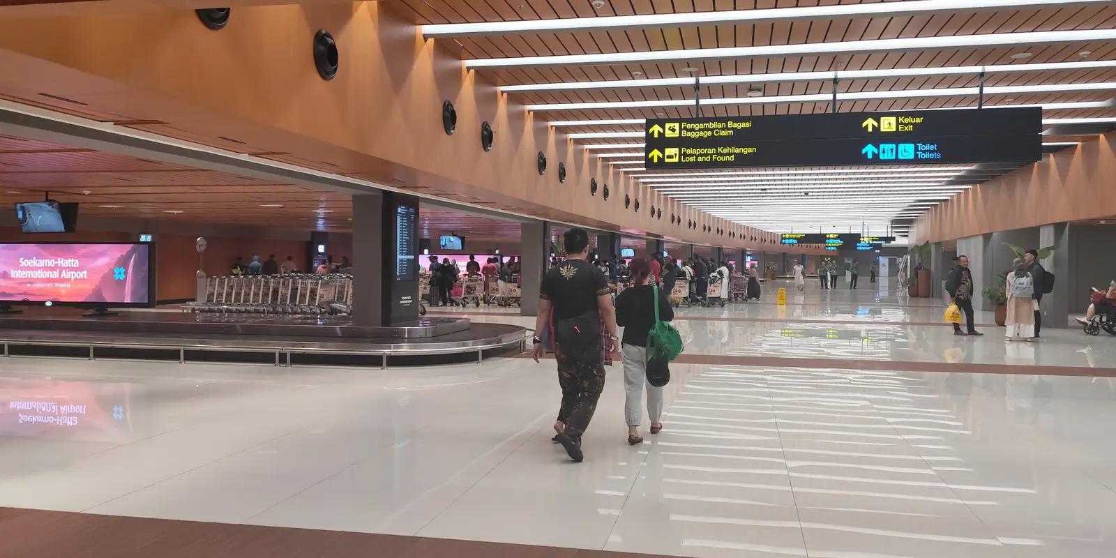 Area kedatangan Terminal 1C Bandara Soekarno-Hatta yang sudah direvitalisasi, dengan conveyor bagasi, papan penunjuk dwibahasa, dan lantai mengilap.